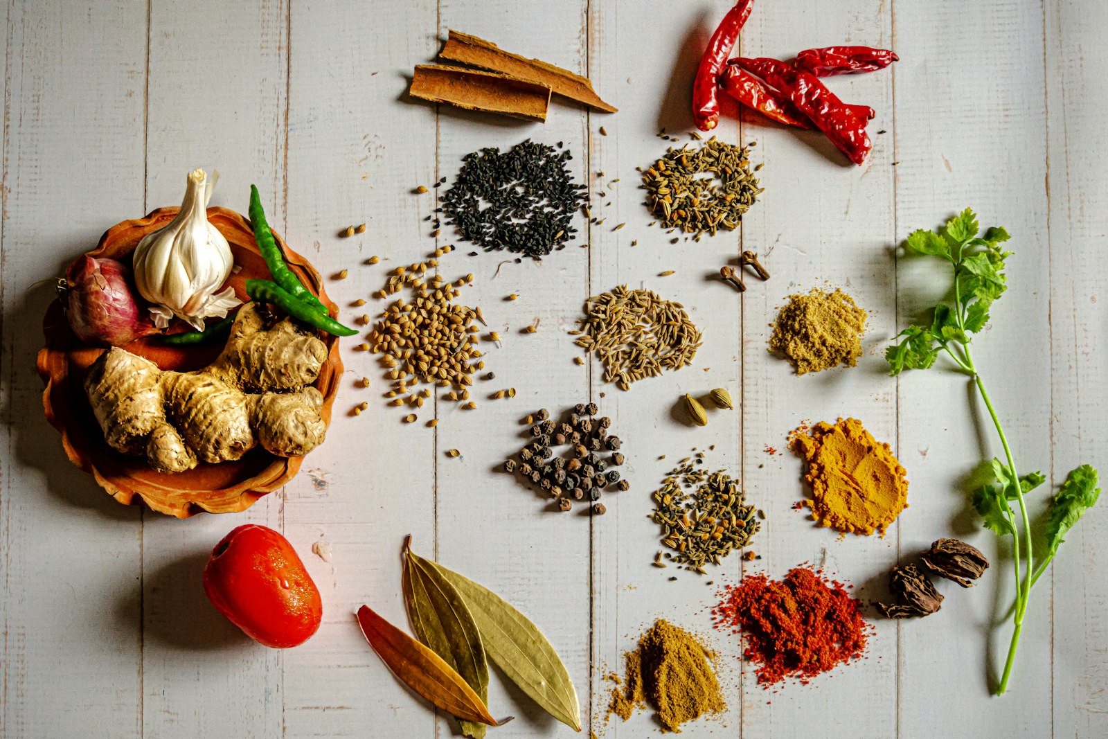 Whole Indian spices, turmeric, chilies, and aromatics arranged on a wooden table