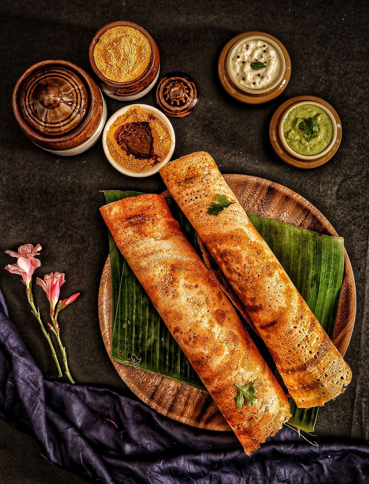 Crispy dosa on a banana leaf with chutneys and spice powders